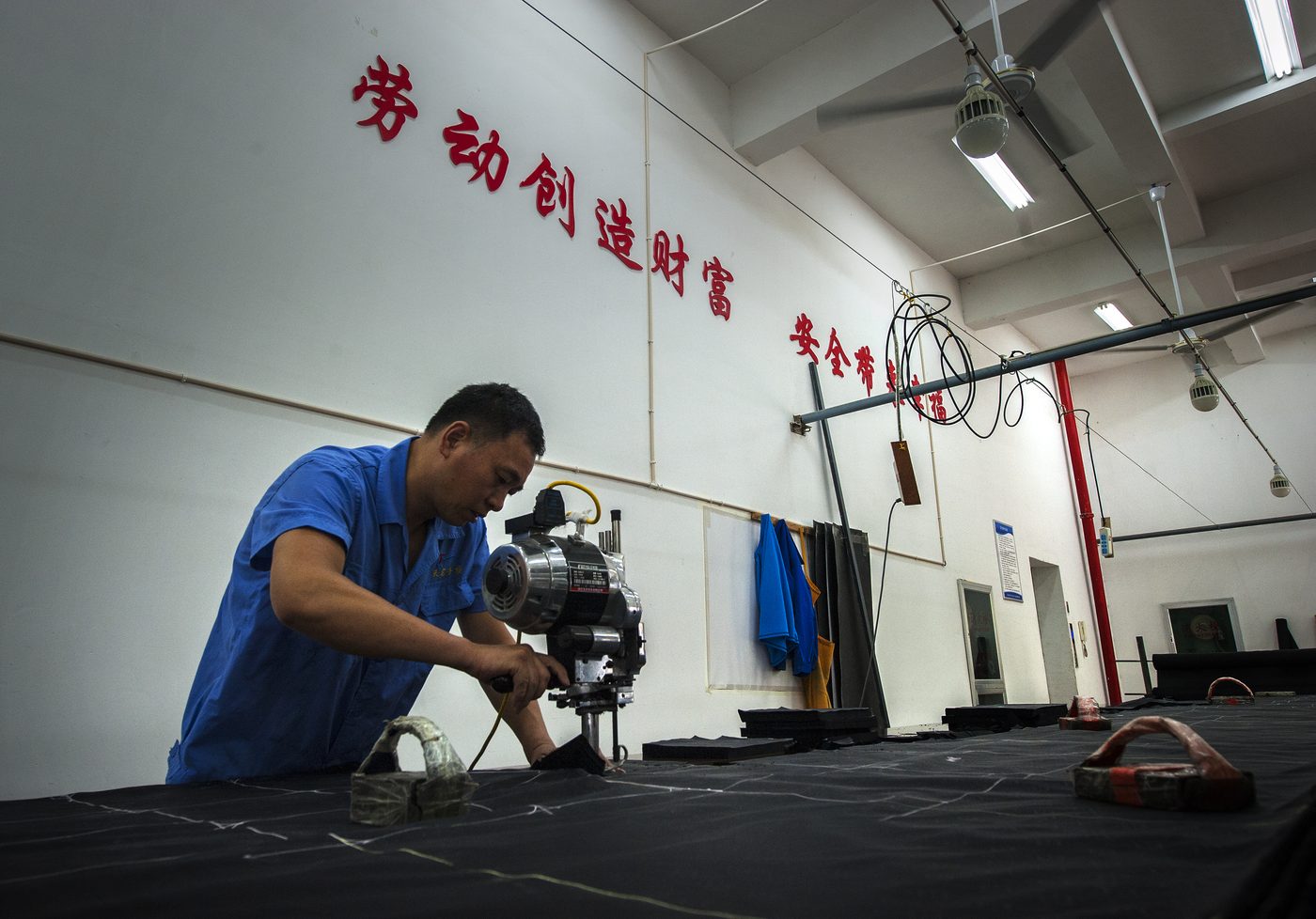 Worker operating a fabric cutting machine